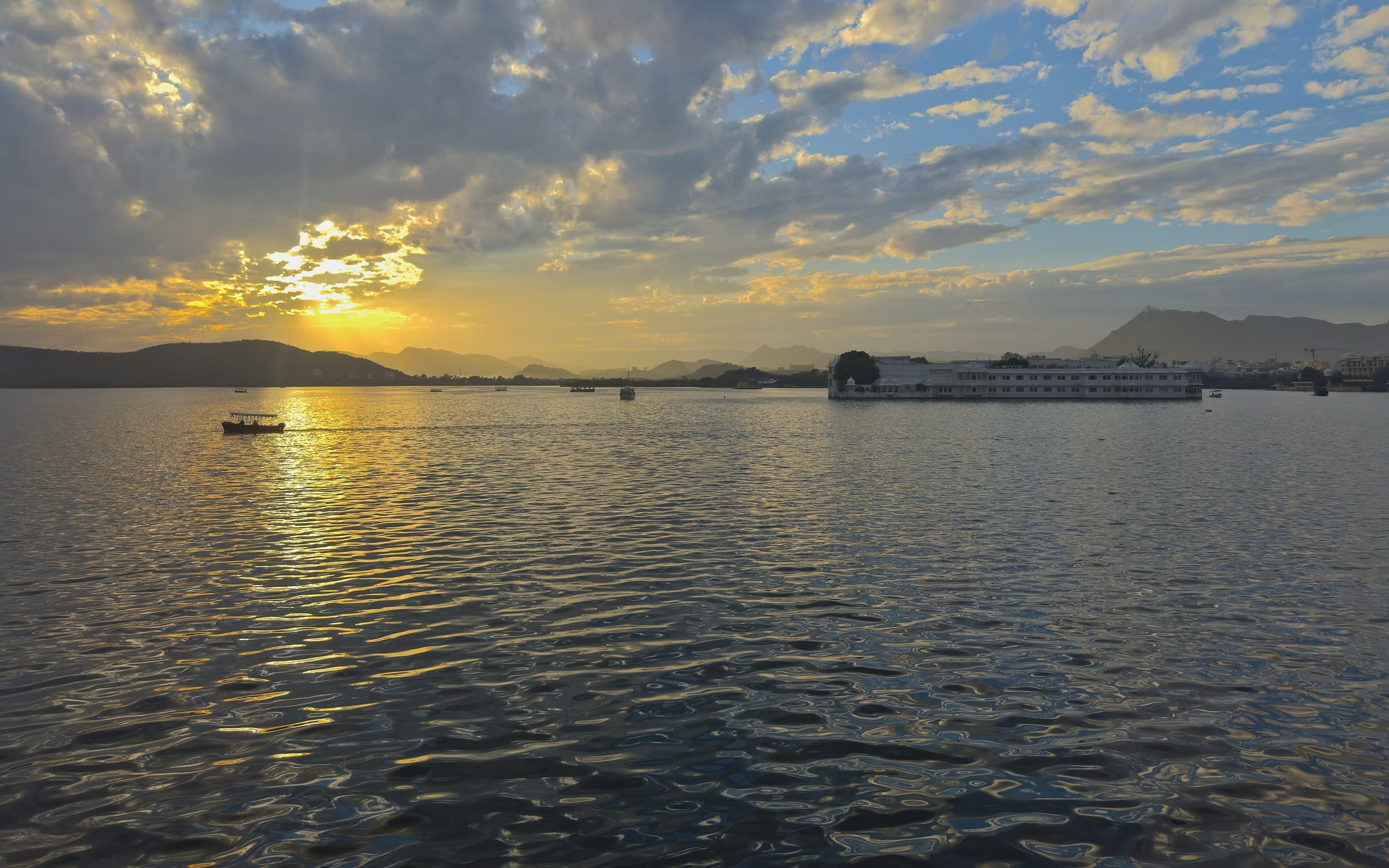 Lake Pichola at sunset in Udaipur, Rajasthan, with the Aravalli hills behind.
